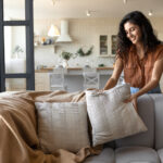 Woman Placing Pillow on Couch and Avoiding Apartment Decorating Mistakes